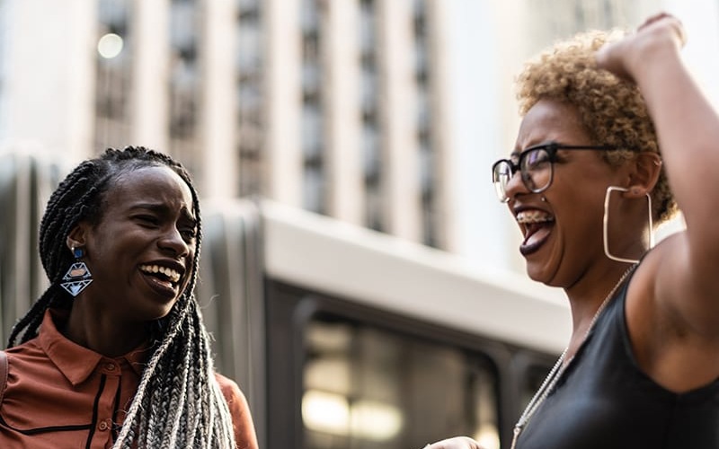 lifestyle image of two women laughing in a city environment
